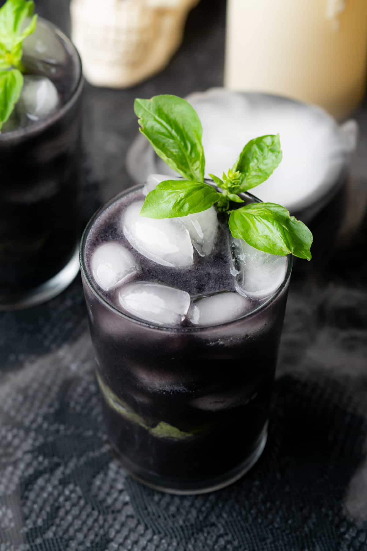 dark black spooky blueberry gin cocktail with basil and dry ice 