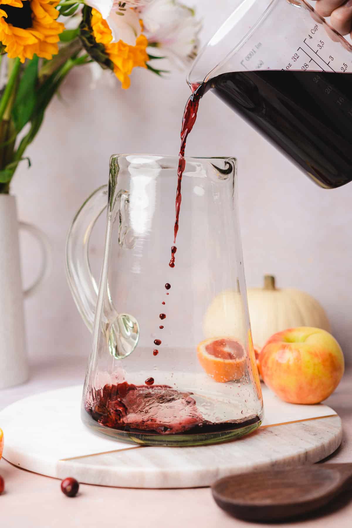 pouring red wine into a large pitcher