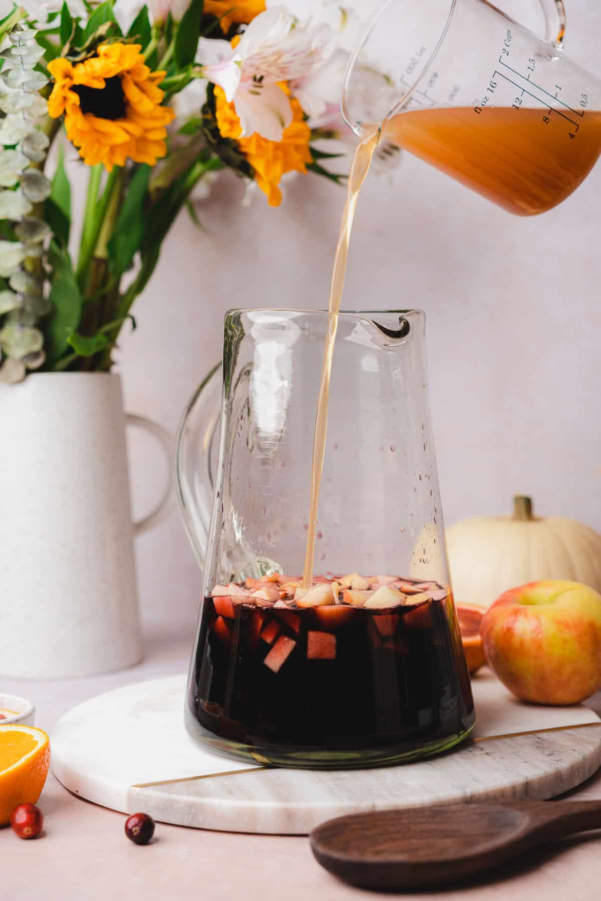 pouring apple cider into a large pitcher to make sangria