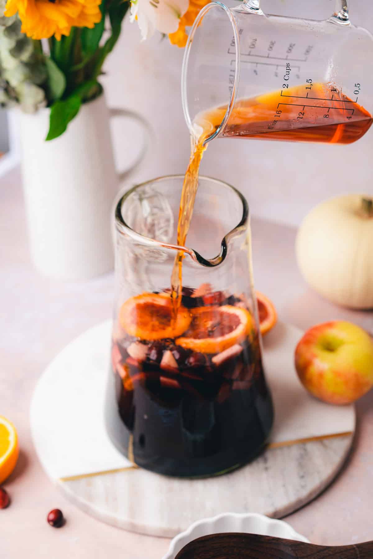 pouring in whiskey to a red wine whiskey sangria pitcher