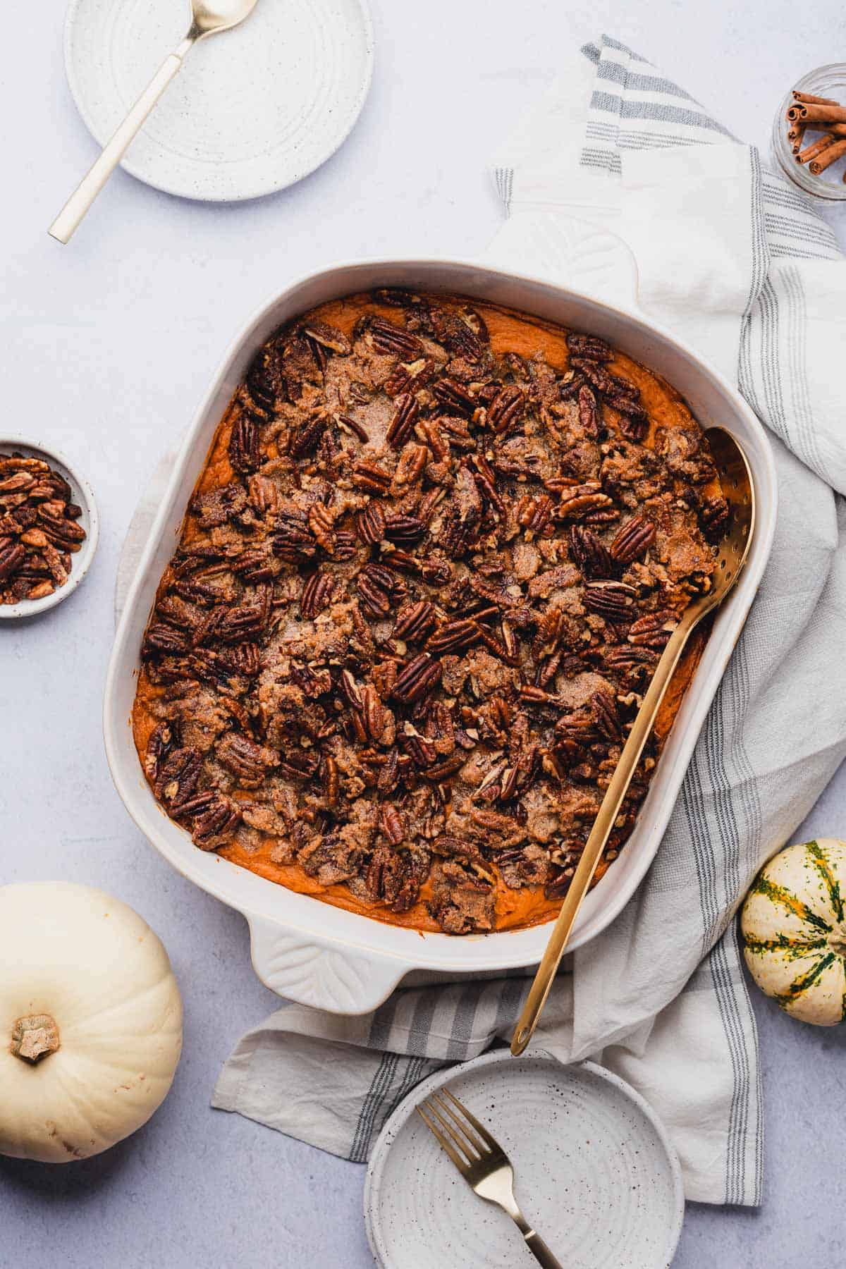 sweet potato casserole in a white baking dish surrounded by small gourds