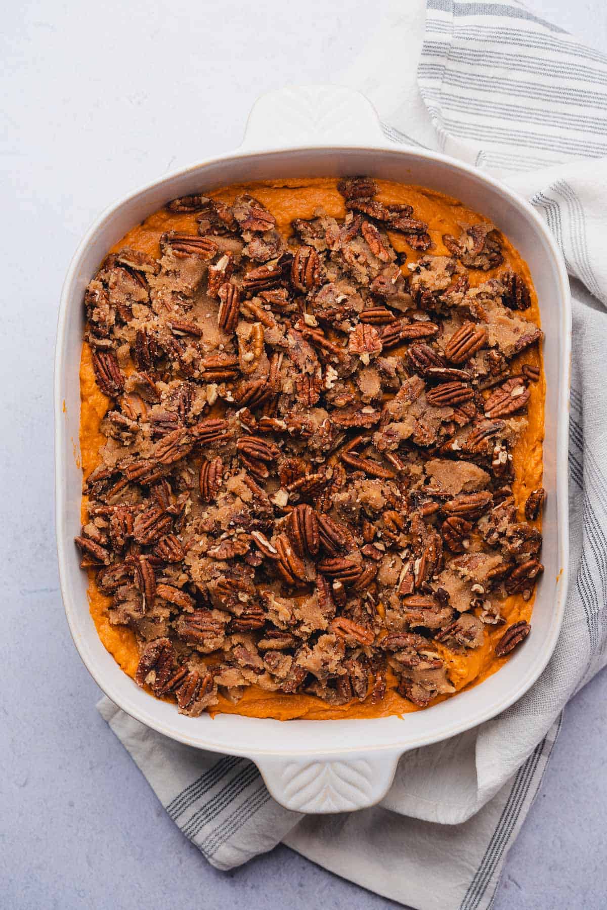 raw pecan crumble topping on top of uncooked sweet potato mash