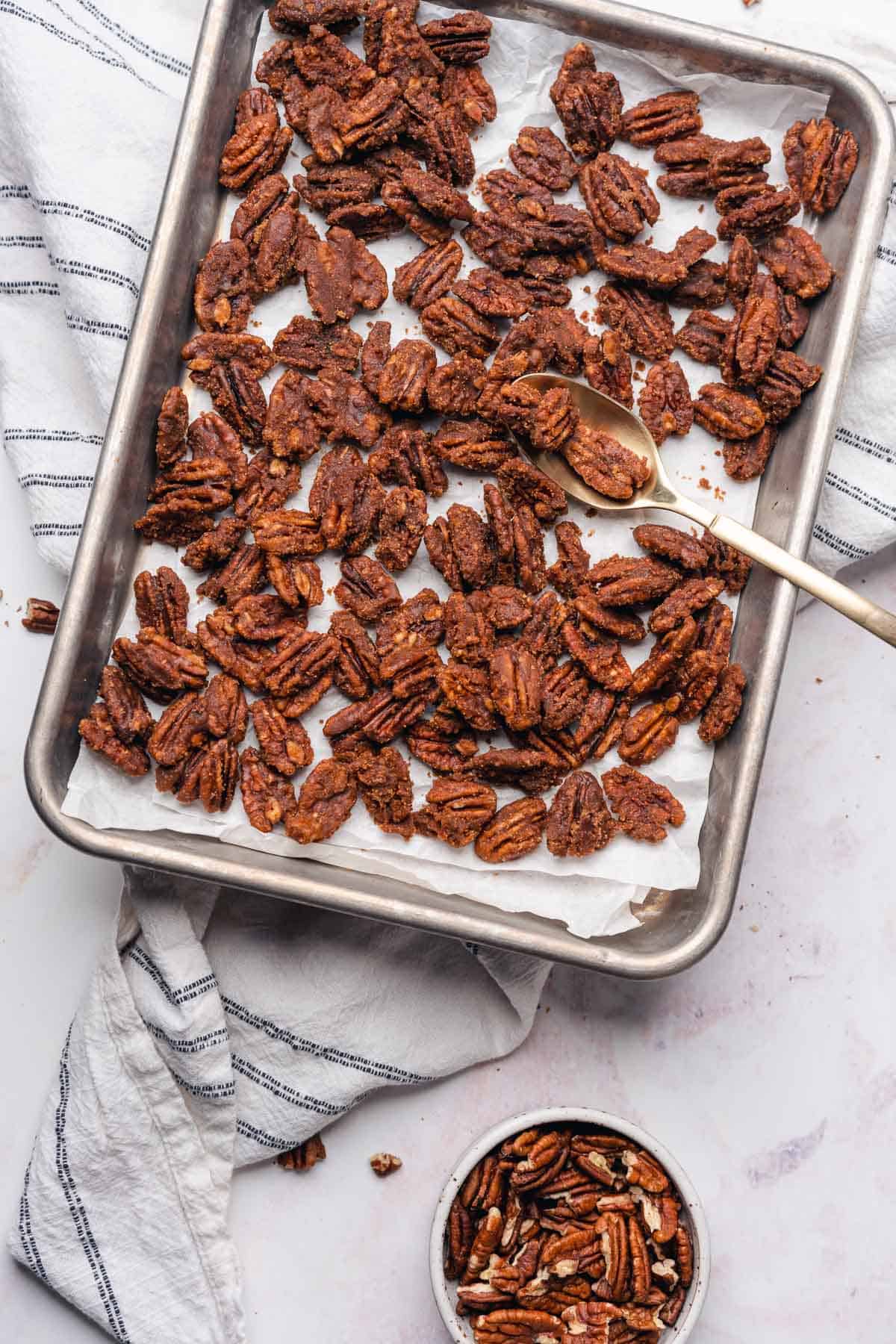 parchment lined baking sheet full of keto candied pecans