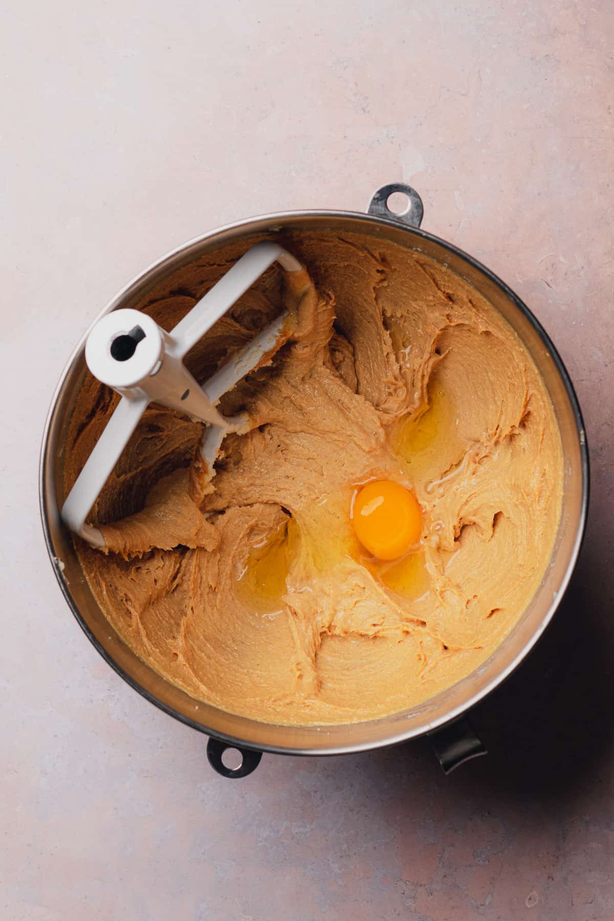 creaming together peanut butter cookie dough with eggs in a mixing bowl with a paddle attachment