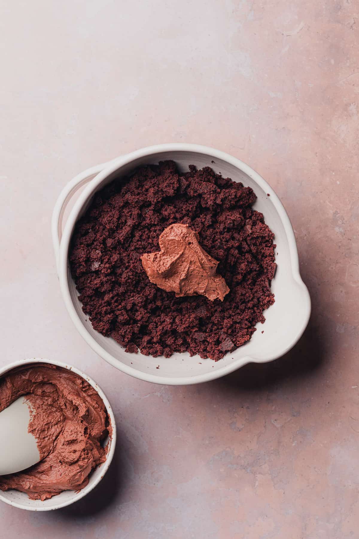 chocolate frosting in the center of a bowl of chocolate cake crumbs 