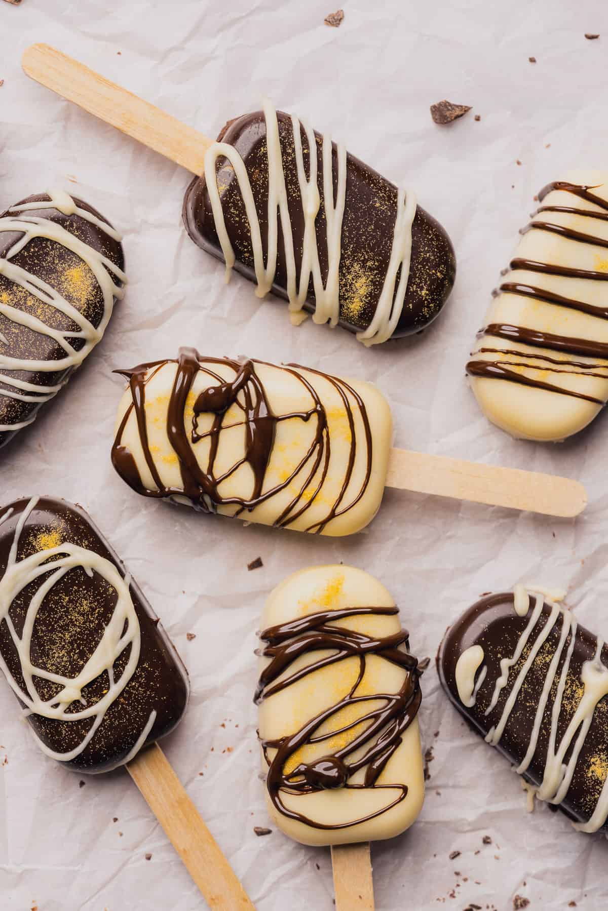 beautiful white chocolate and dark chocolate cakesicles with gold glitter and chocolate drizzle