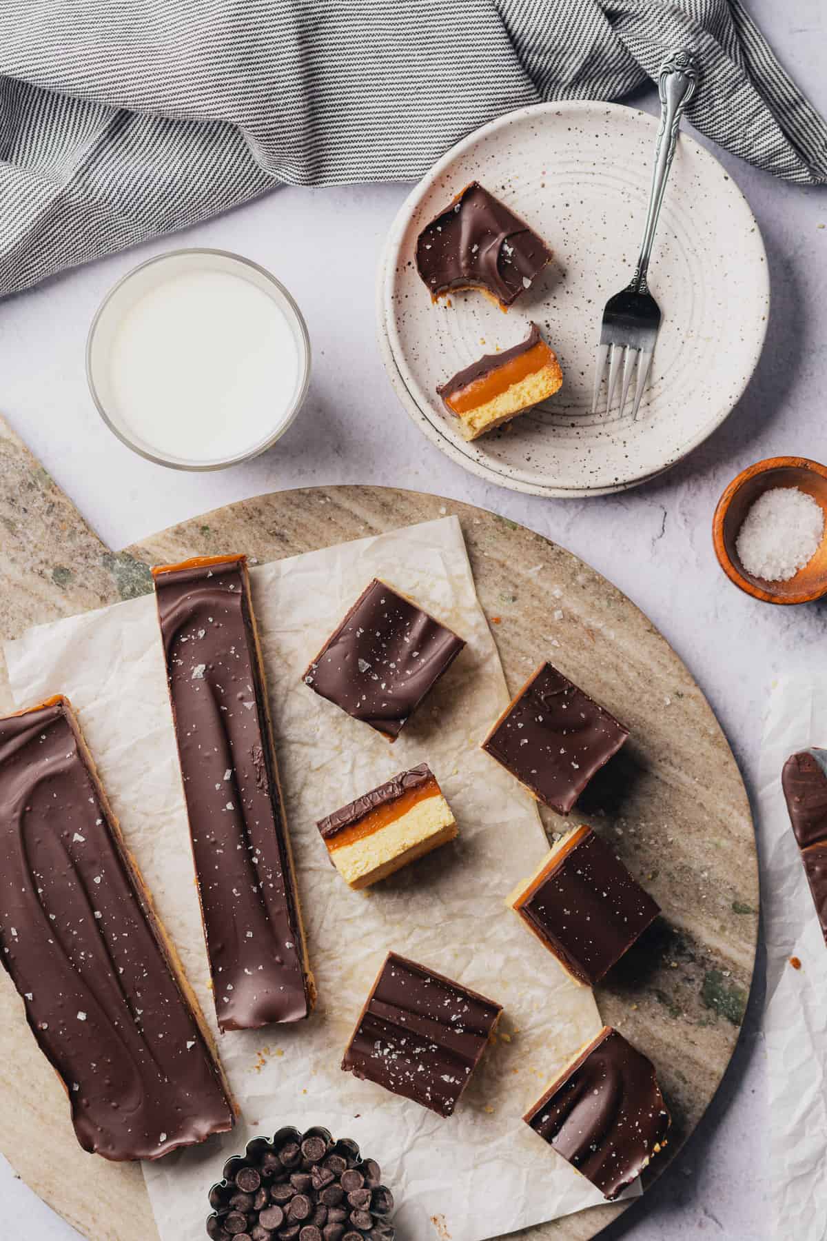 lovely overhead scene of salted chocolate caramel slices with milk and flakey sea salt