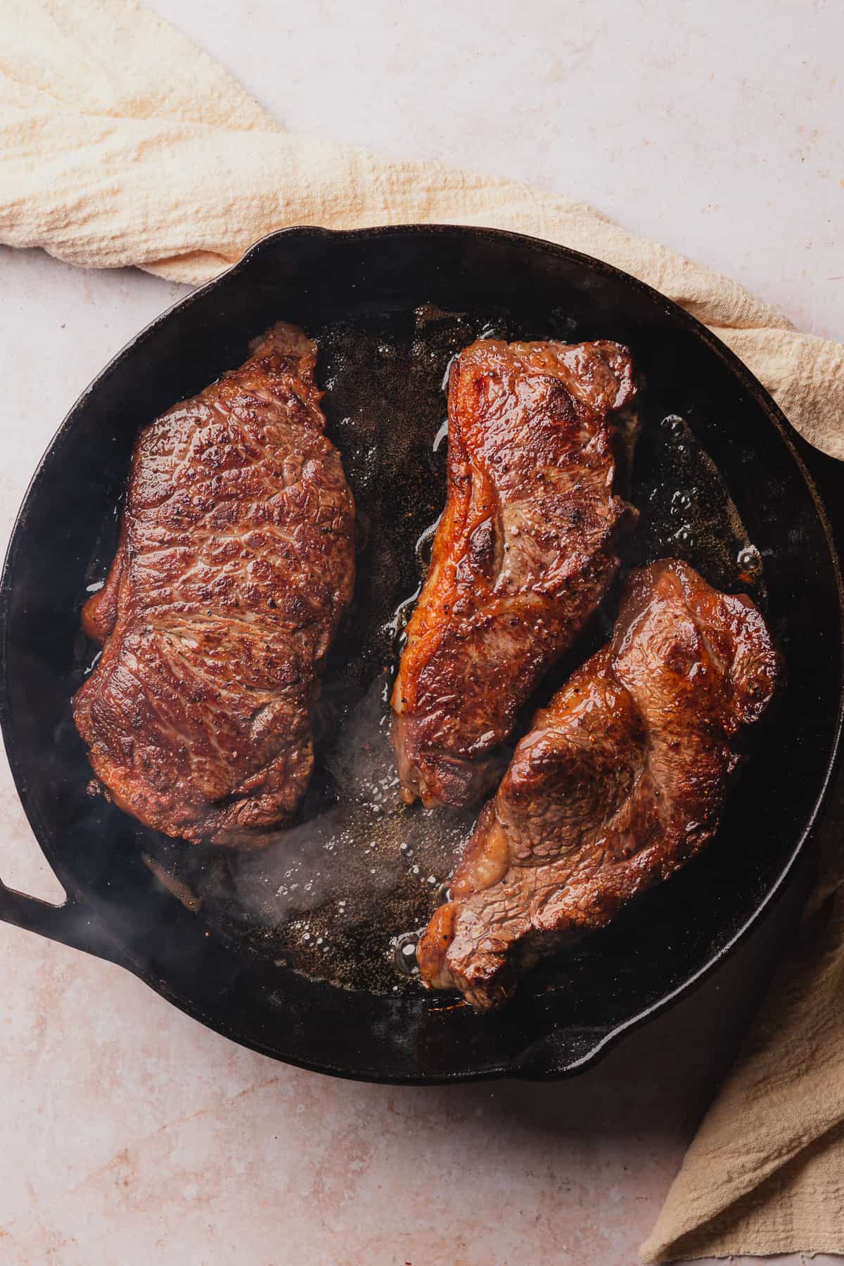 steaks searing in a cast iron skillet
