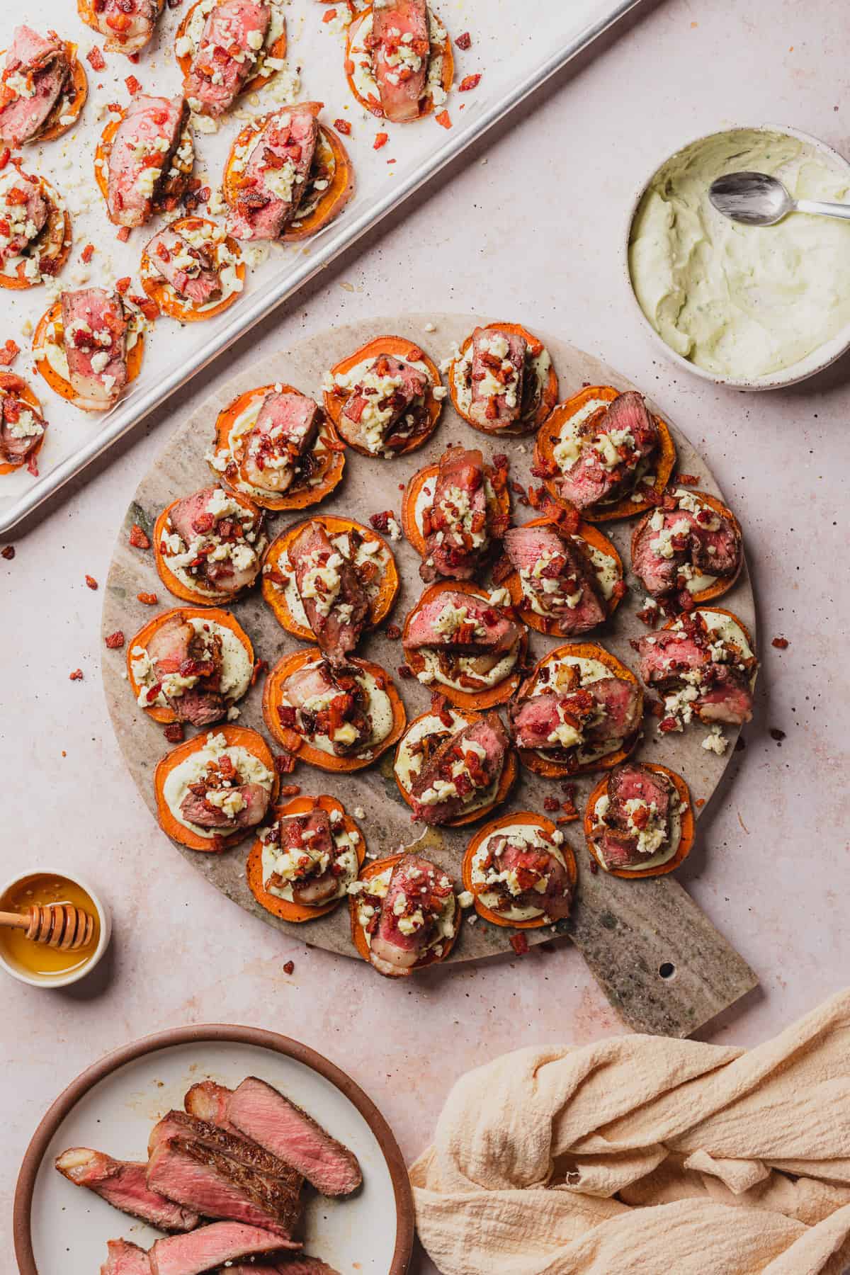 tray full of steak appetizers on sweet potato rounds with blue cheese, bacon and caramelized onions