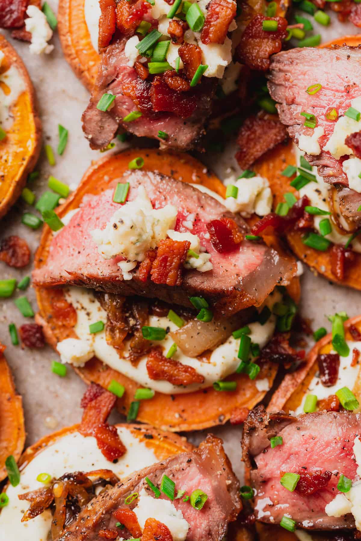 flay lay of steak appetizers with chives bacon and blue cheese on a sweet potato round