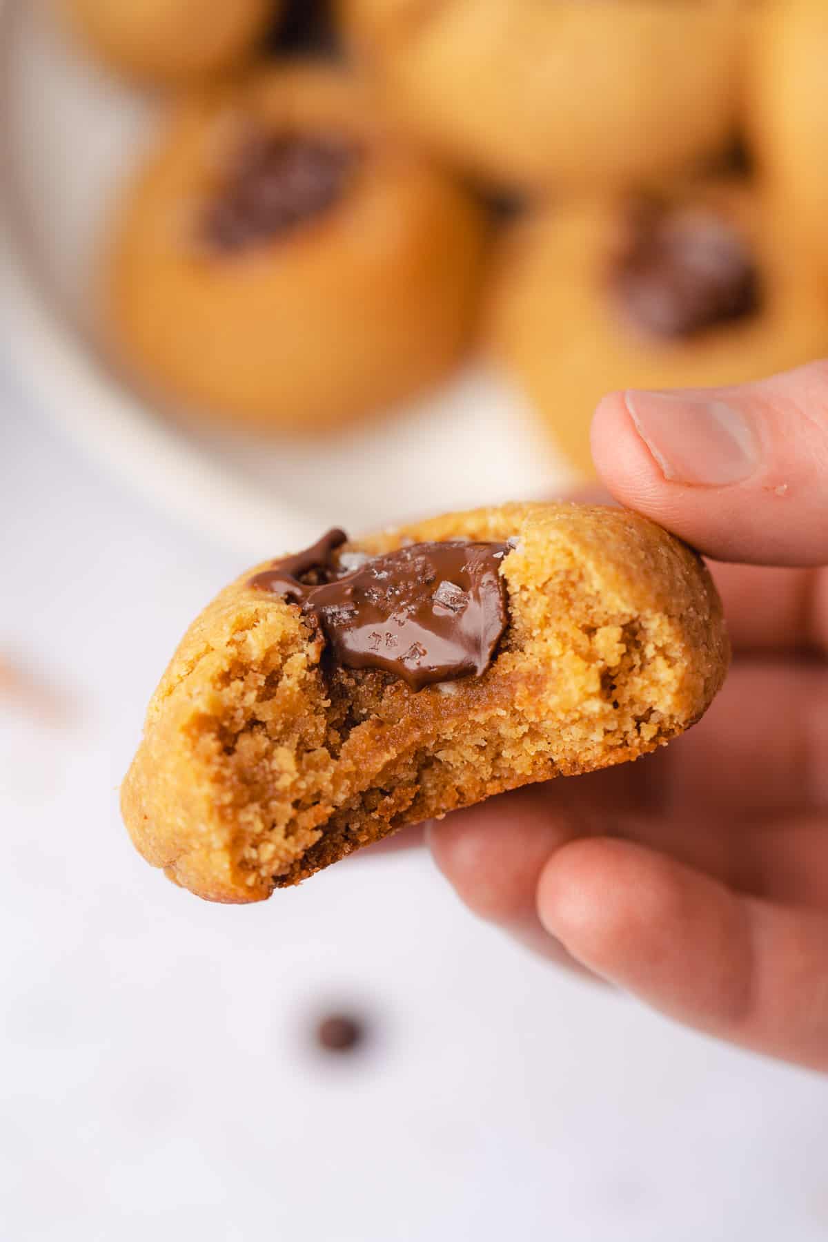 hand held stack of gluten free peanut butter blossoms with a bite taken out to show the gooey chocolate center 