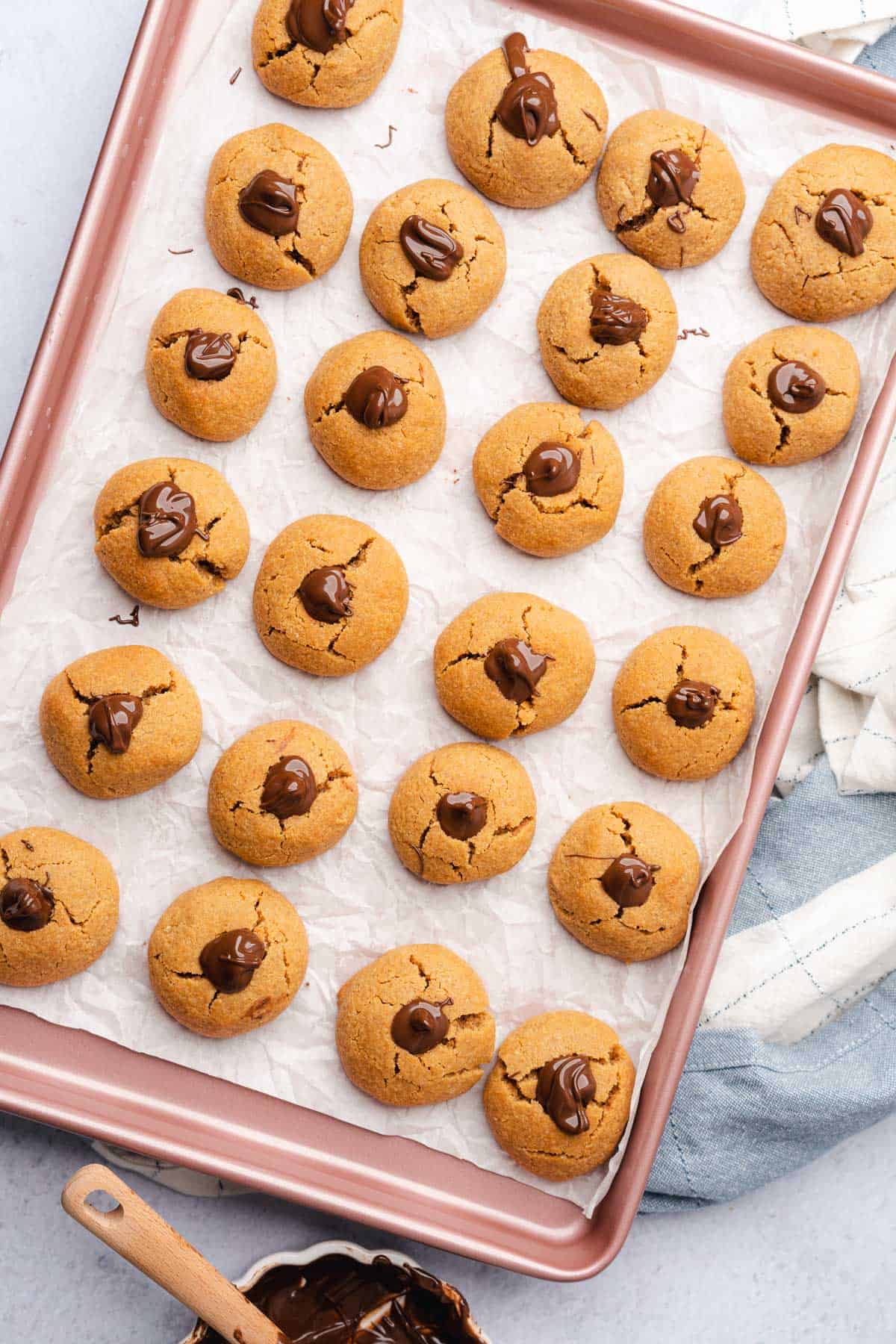 gluten free peanut butter blossoms on a baking sheet filled with chocoalte 