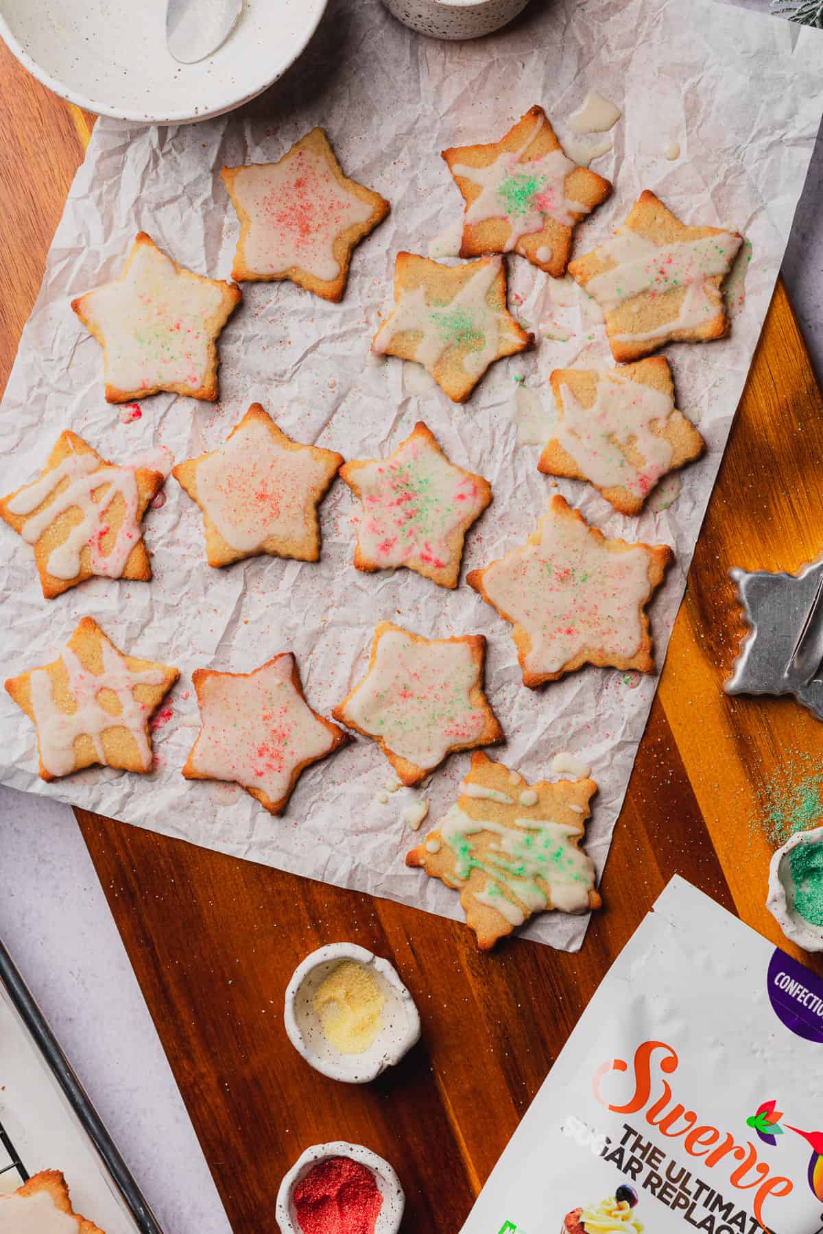 parchment paper on a wooden board full of iced gluten free star cookies
