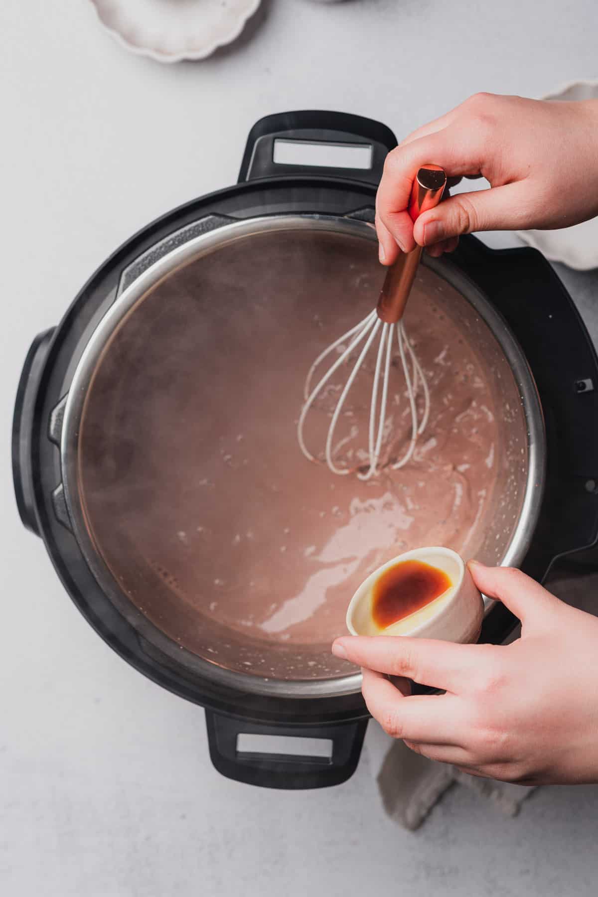 hand pouring in vanilla extract to an instant pot 