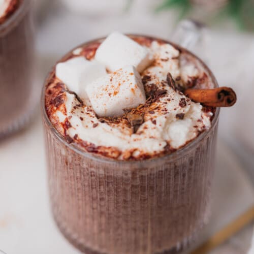 straight on shot of instant pot hot chocolate with whipped cream, cinnamon, chocolate shavings and marshmallows