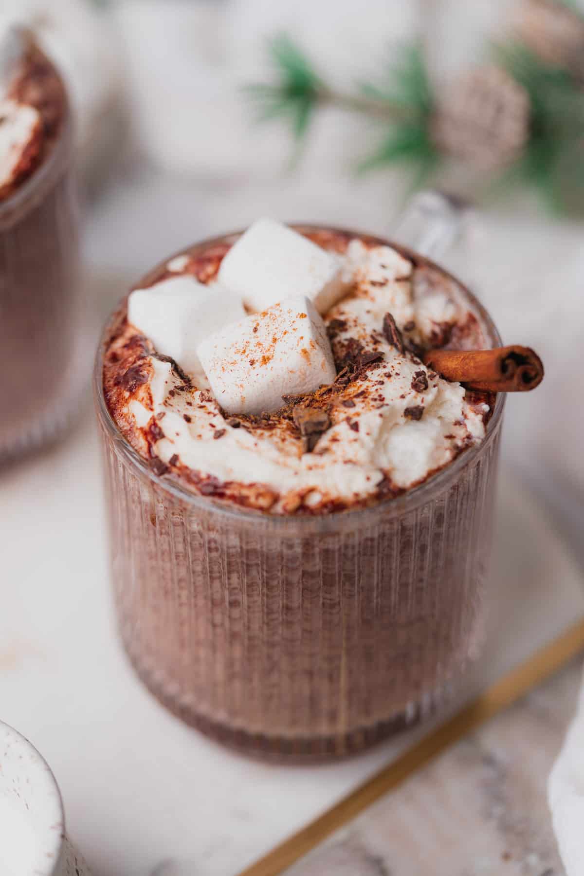 straight on shot of instant pot hot chocolate with whipped cream, cinnamon, chocolate shavings and marshmallows