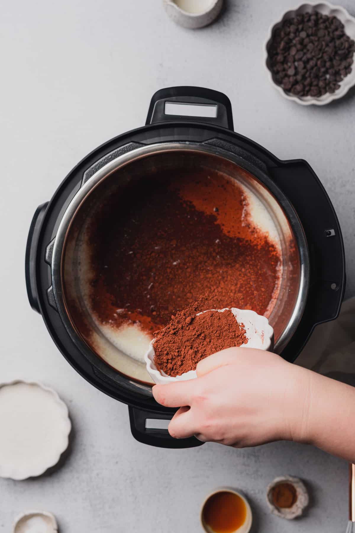 hand pouring in dutch process cocoa powder to milk in an instant pot 