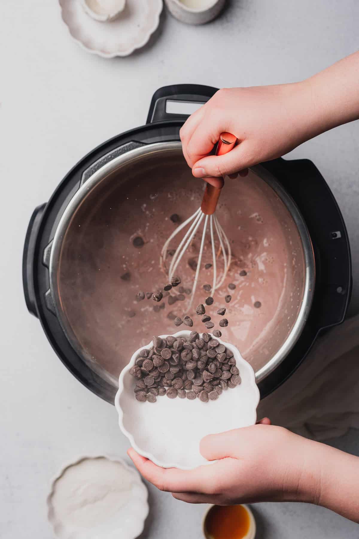 pouring chocolate chips into an instant pot while making hot chocolate 