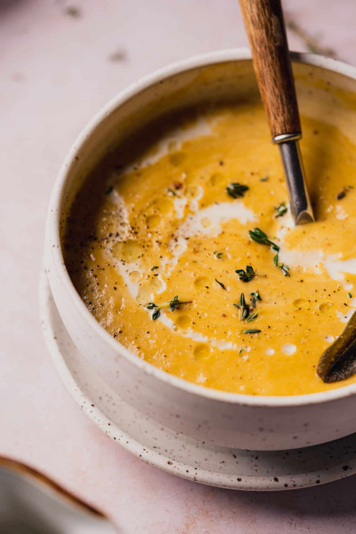 close up shot of a bowl of super creamy keto butternut squash soup with fresh herbs, cream