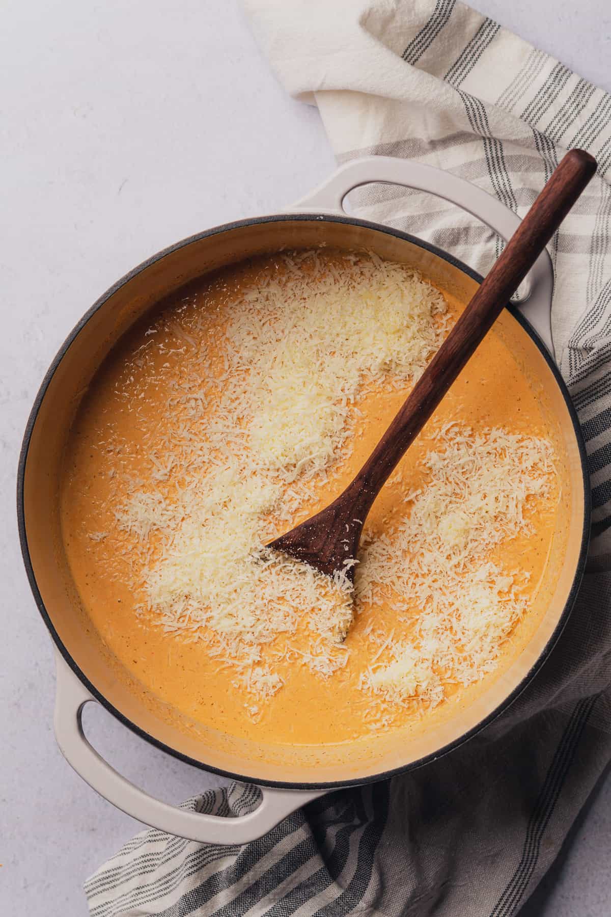stirring in freshly grated parmesan cheese to a shrimp bisque soup  