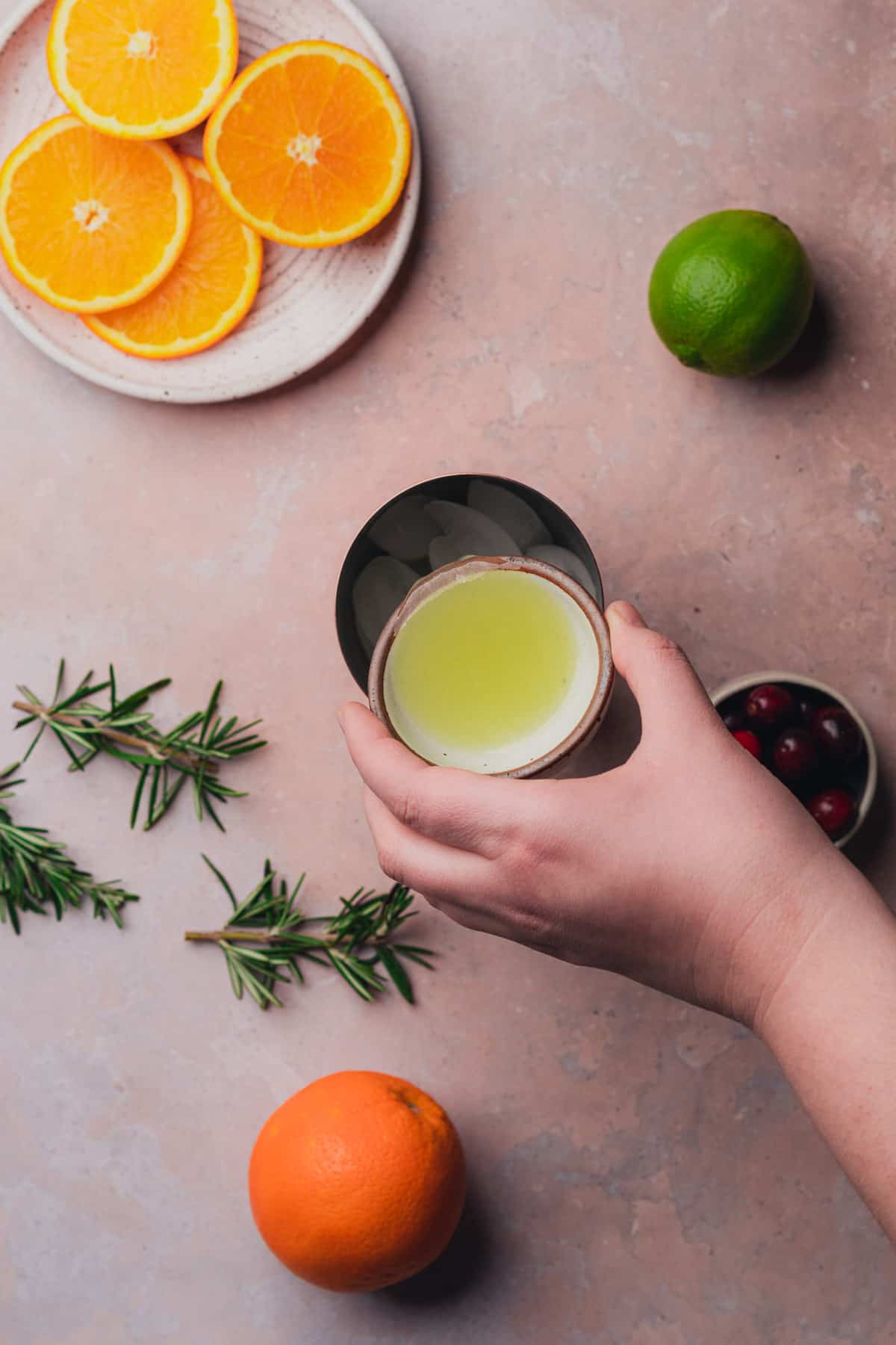 hand pouring in lime juice to a cocktail shaker