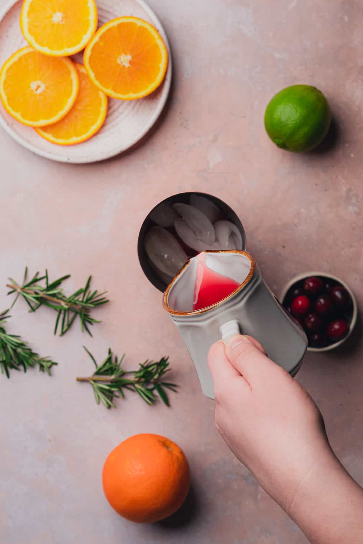 hand pouring in cranberry juice to a cocktail shaker