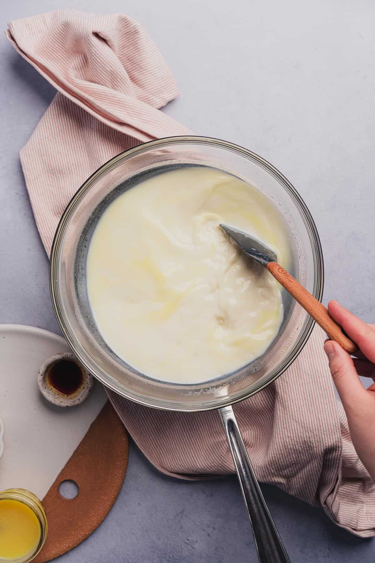 rubber spatula stirring white chocolate chips and milk together in a double boiler