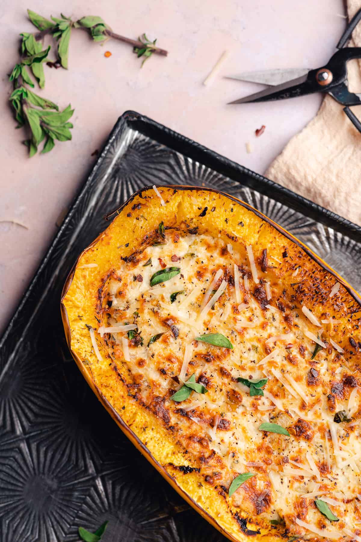 cooked air fryer spaghetti squash on a textured baking sheet with fresh herbs