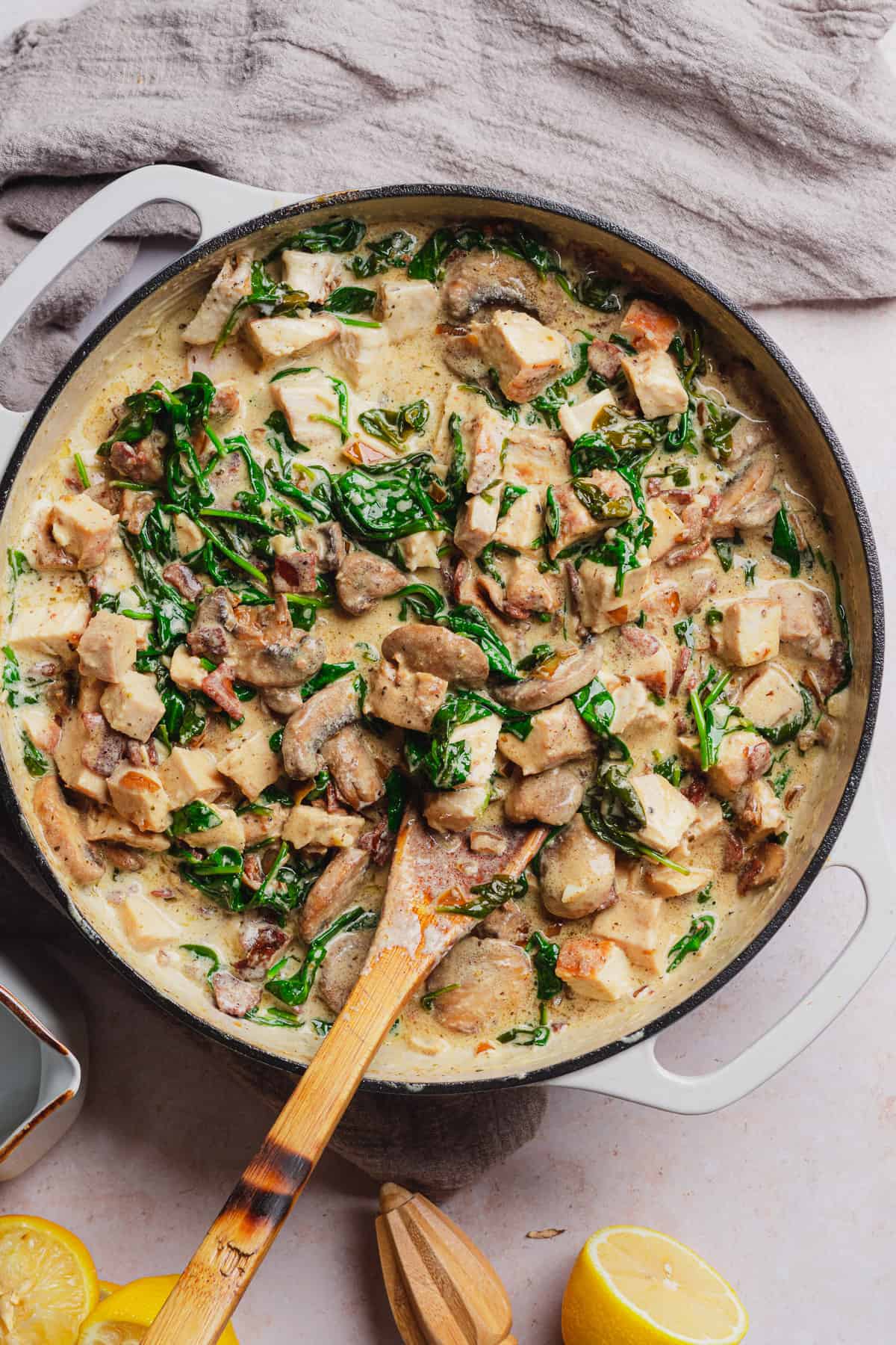 creamy chicken bacon mushroom pasta sauce with spinach in an enameled dutch oven