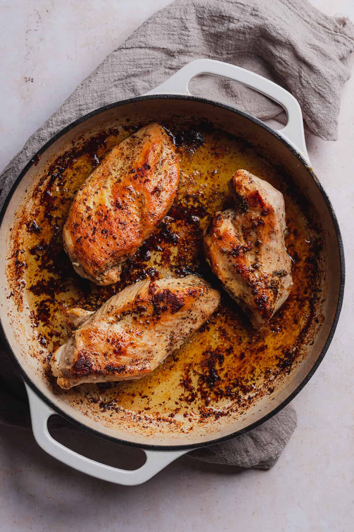 brown and seared chicken breasts in an enameled skillet