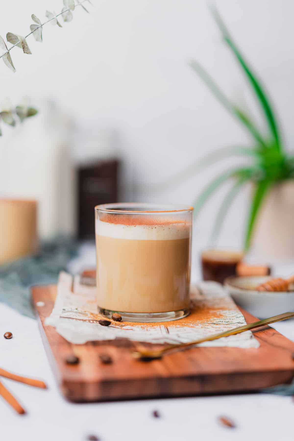 stunning cafe con miel coffee with an aloe vera plant in the background, coffee beans and a dusting of cinnamon