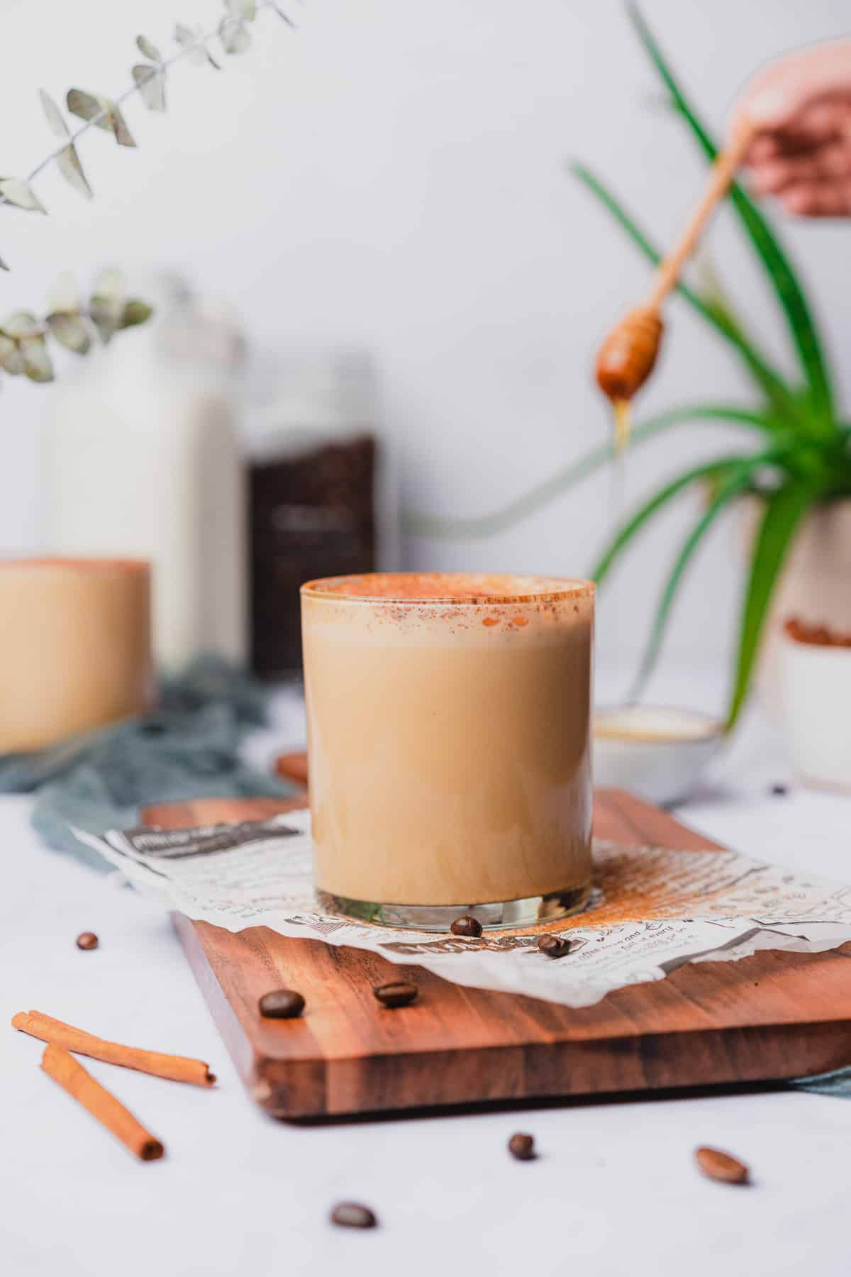 hot miel spanish coffee with honey and a honey dripper in the background by an aloe vera plant