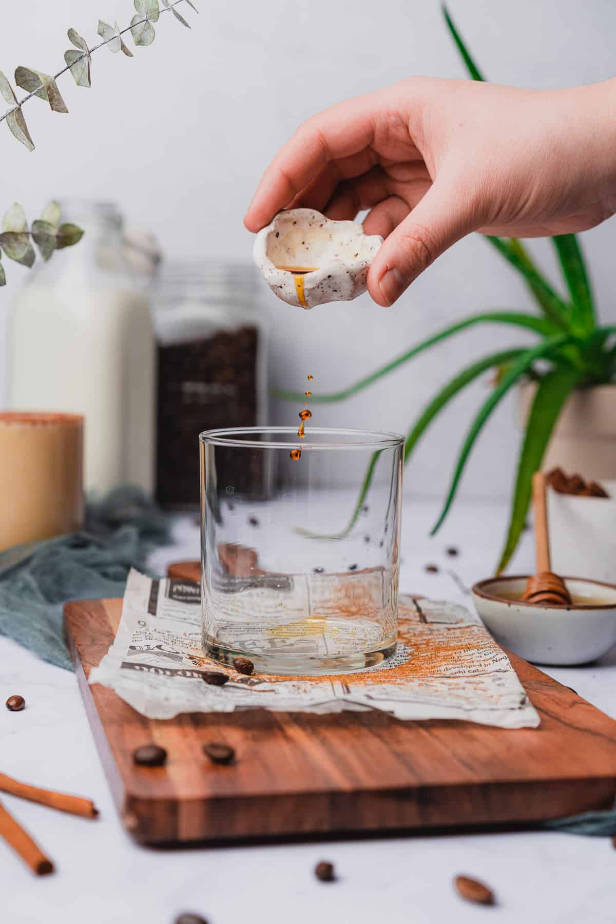 hand pouring vanilla extract into the bottom of a glass 