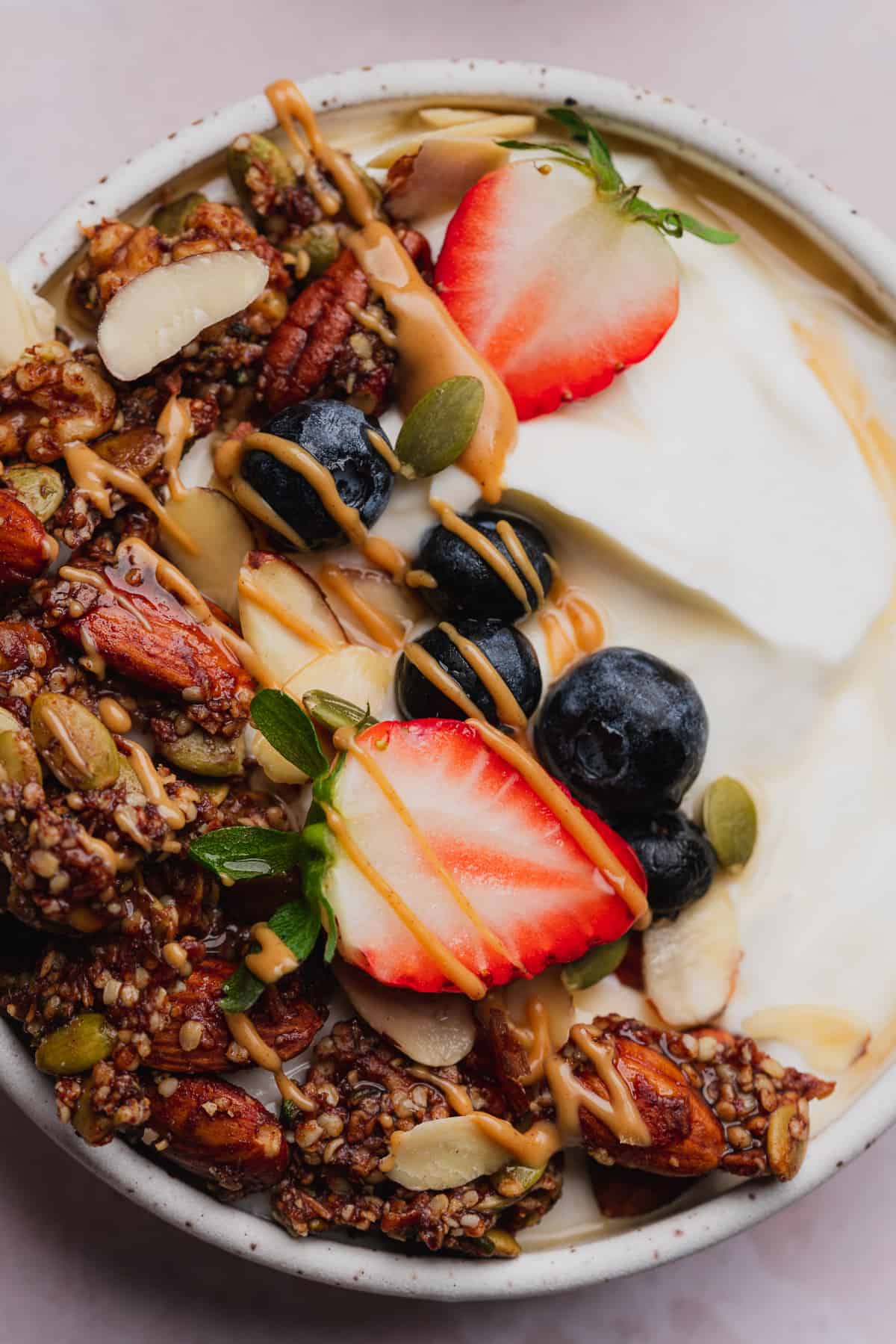 very close up shot of a yogurt with granola and fruit bowl. 