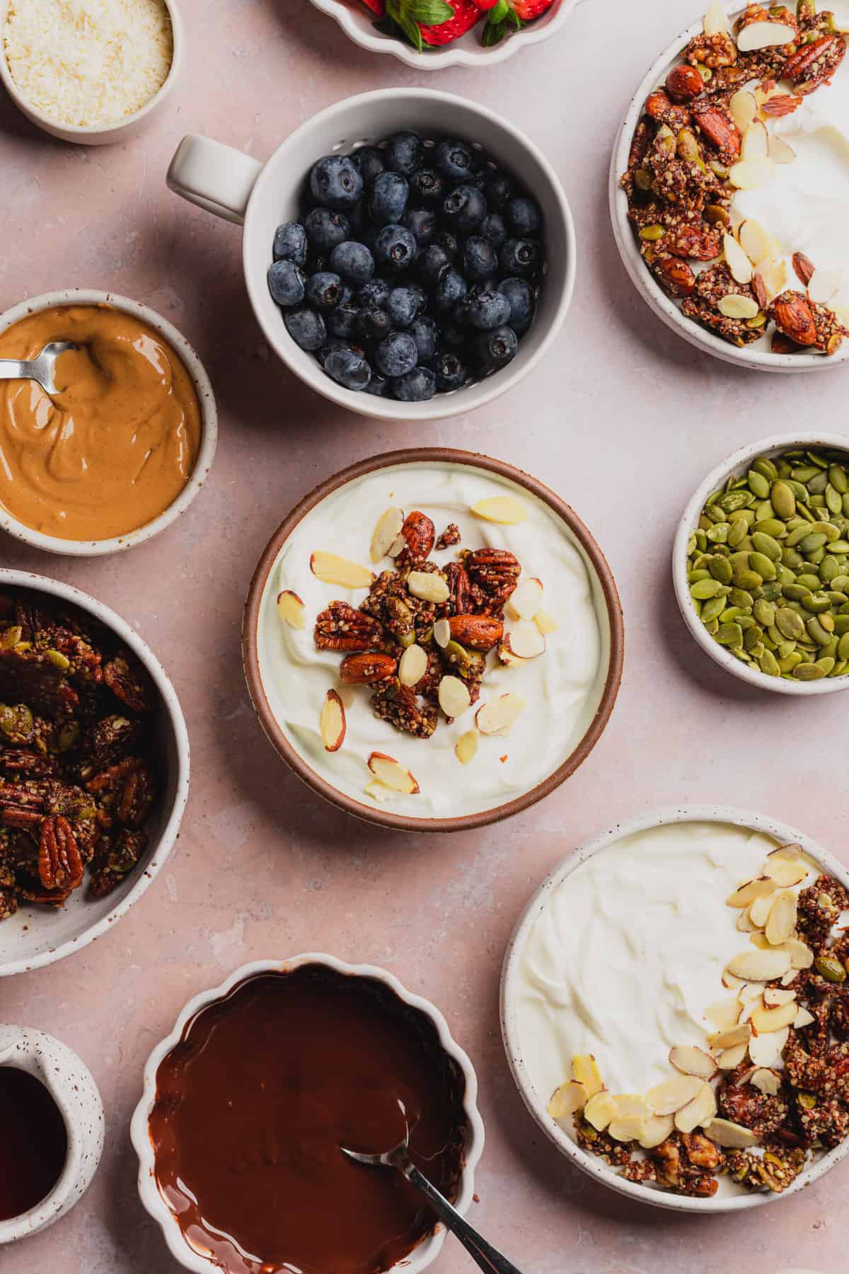 greek yogurt topped with granola, nuts, and drizzled with maple syrup by being surrounded by other toppings. 