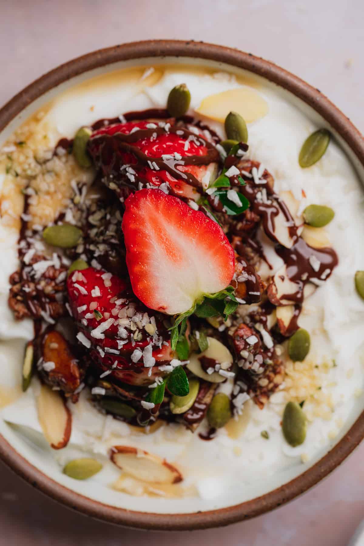 close up shot of a yogurt bowl with fruit, granola, chocolate, hemp hearts, and pepitas. 