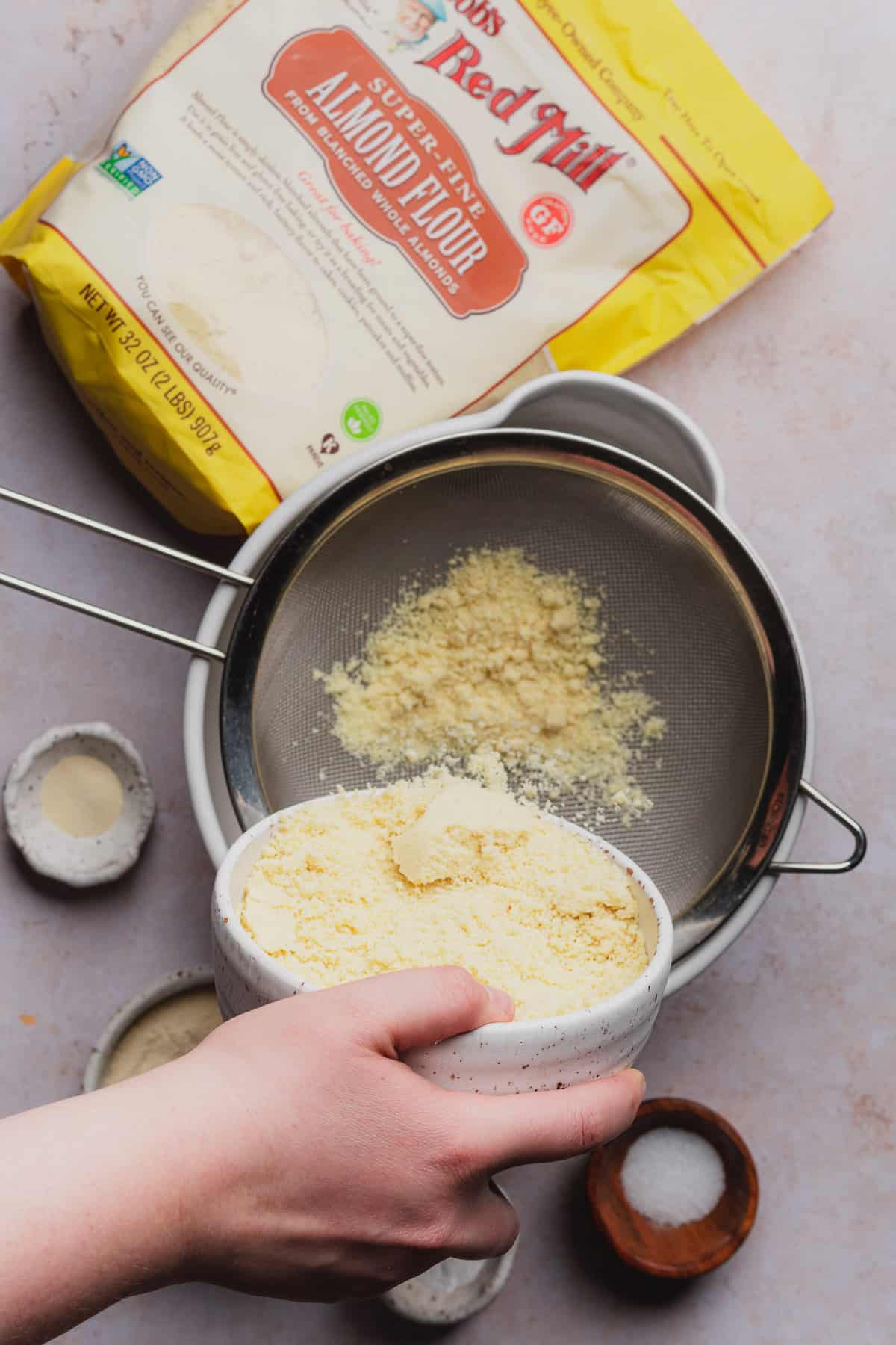 hand pouring in dry ingredients for cookies through a sifter 
