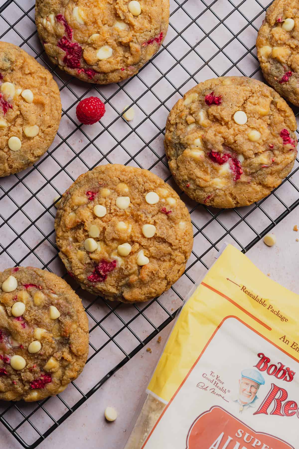 close up shot of raspberry and white chocolate cookies with a bag of bob's red mill almond flour 