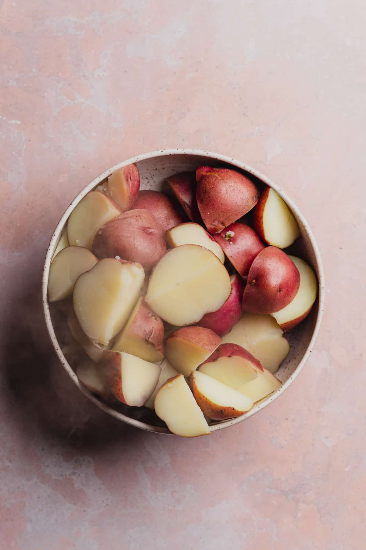 boiled red skin potatoes in a large bowl with steam coming off