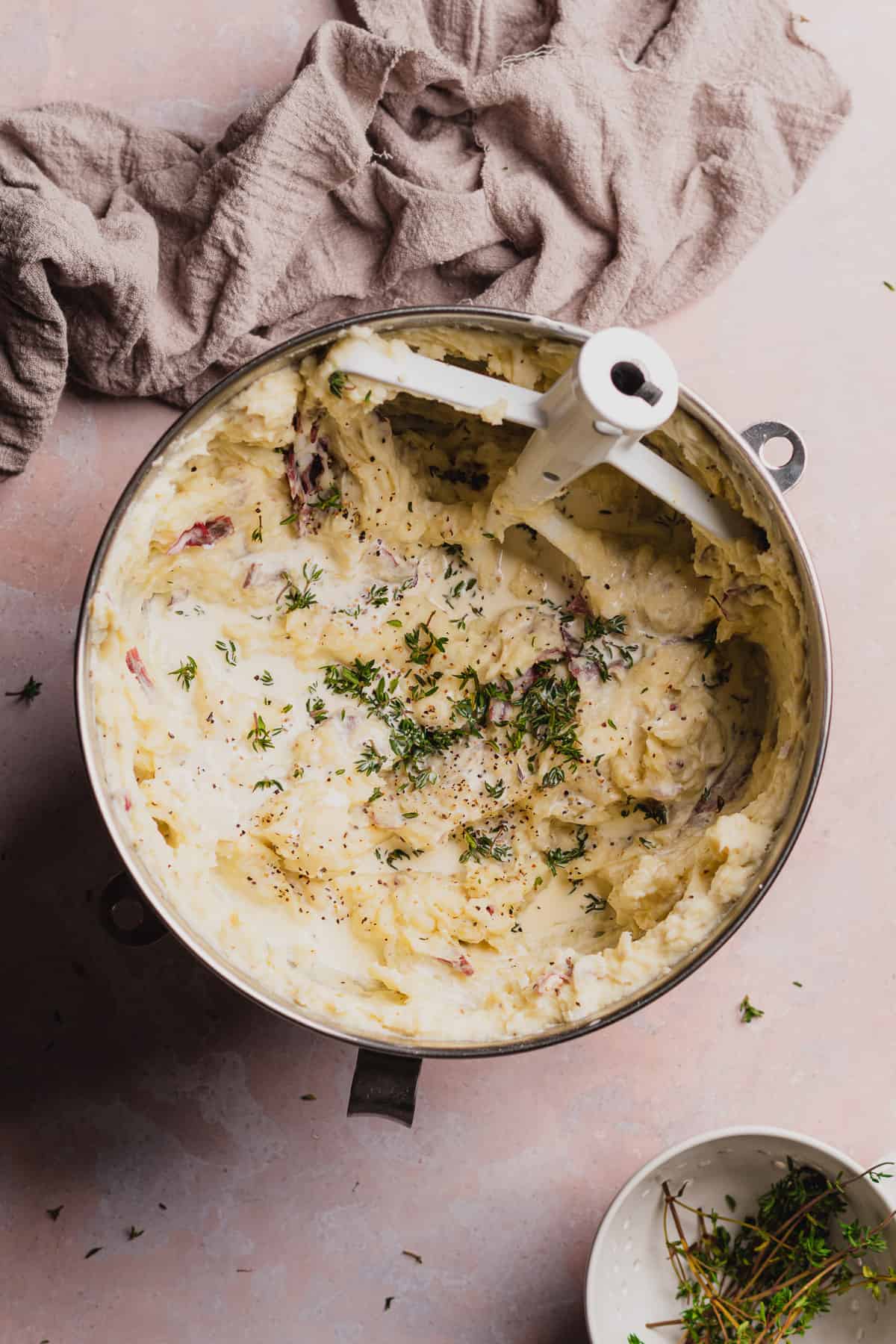 mashed potatoes with fresh thyme in a stand mixer bowl with a paddle attachement