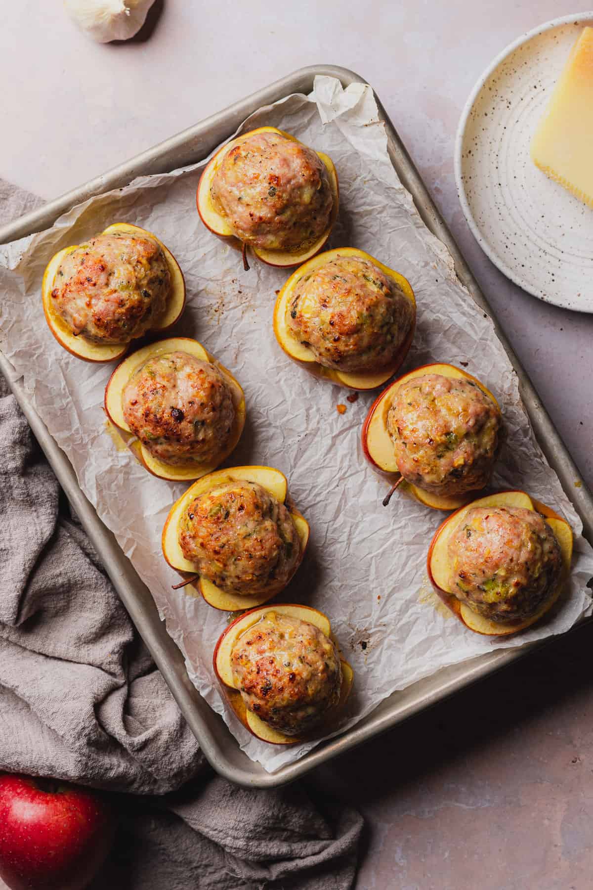 roasted pork sausage stuffed apples baked on a baking sheet with parchment. 