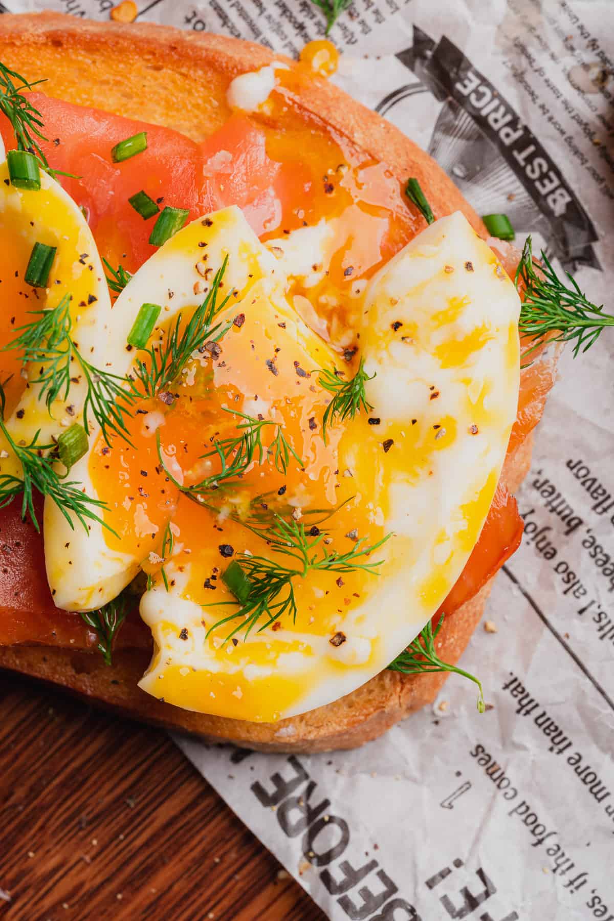 beautiful close up shot of a smashed soft boiled egg with smoked salmon, fresh dill, salt and pepper 