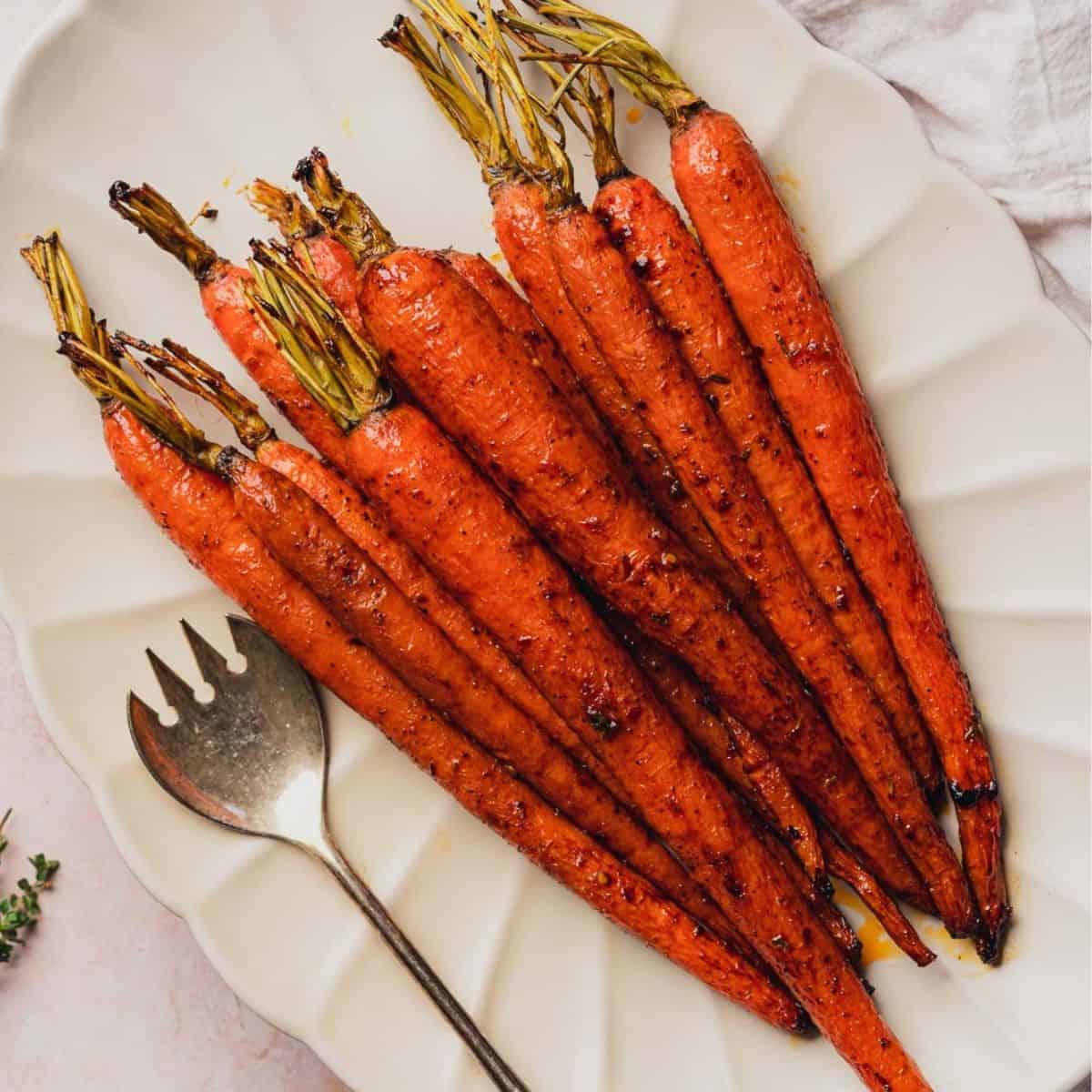maple glazed carrots with green tops on scalloped plate