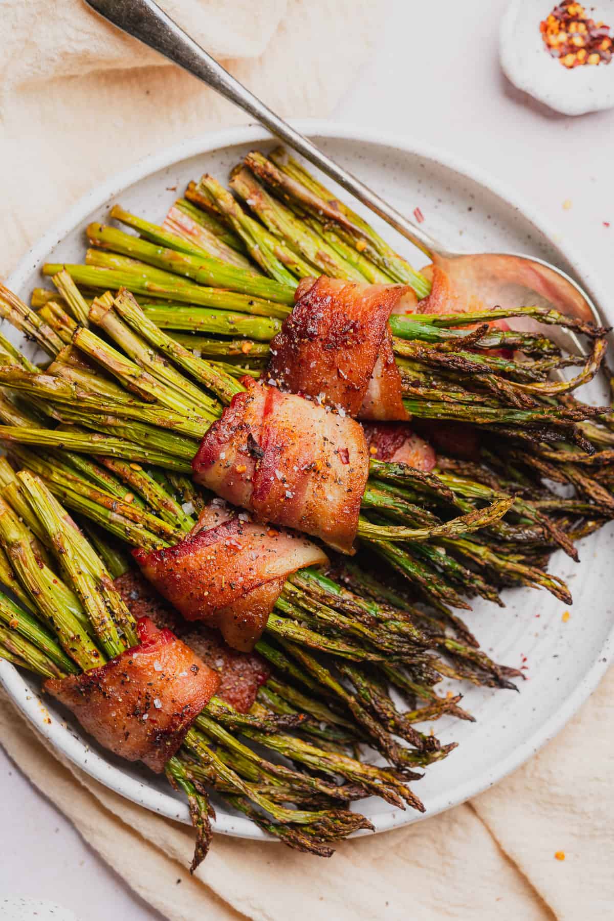 air fryer bacon wrapped asparagus bundles on a white plate 