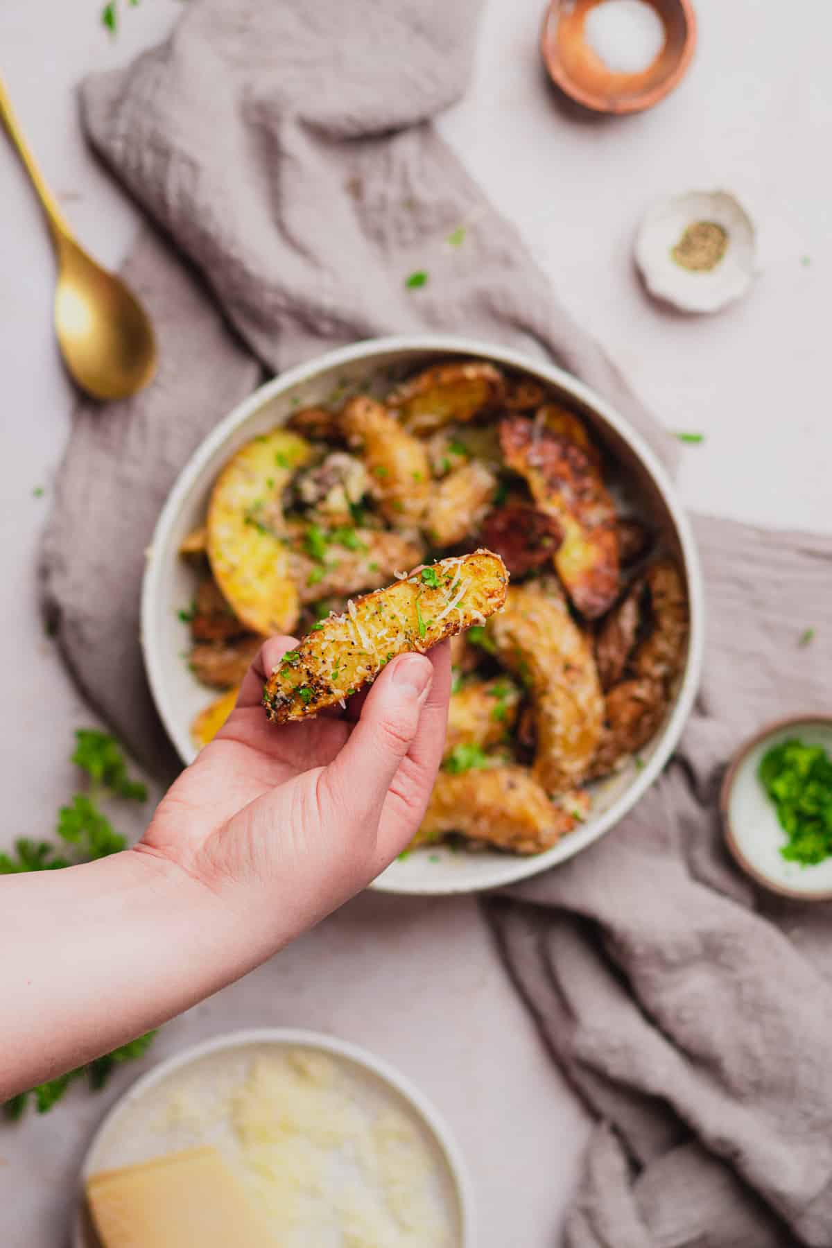 hand holding a potato with parmesan cheese and parsley