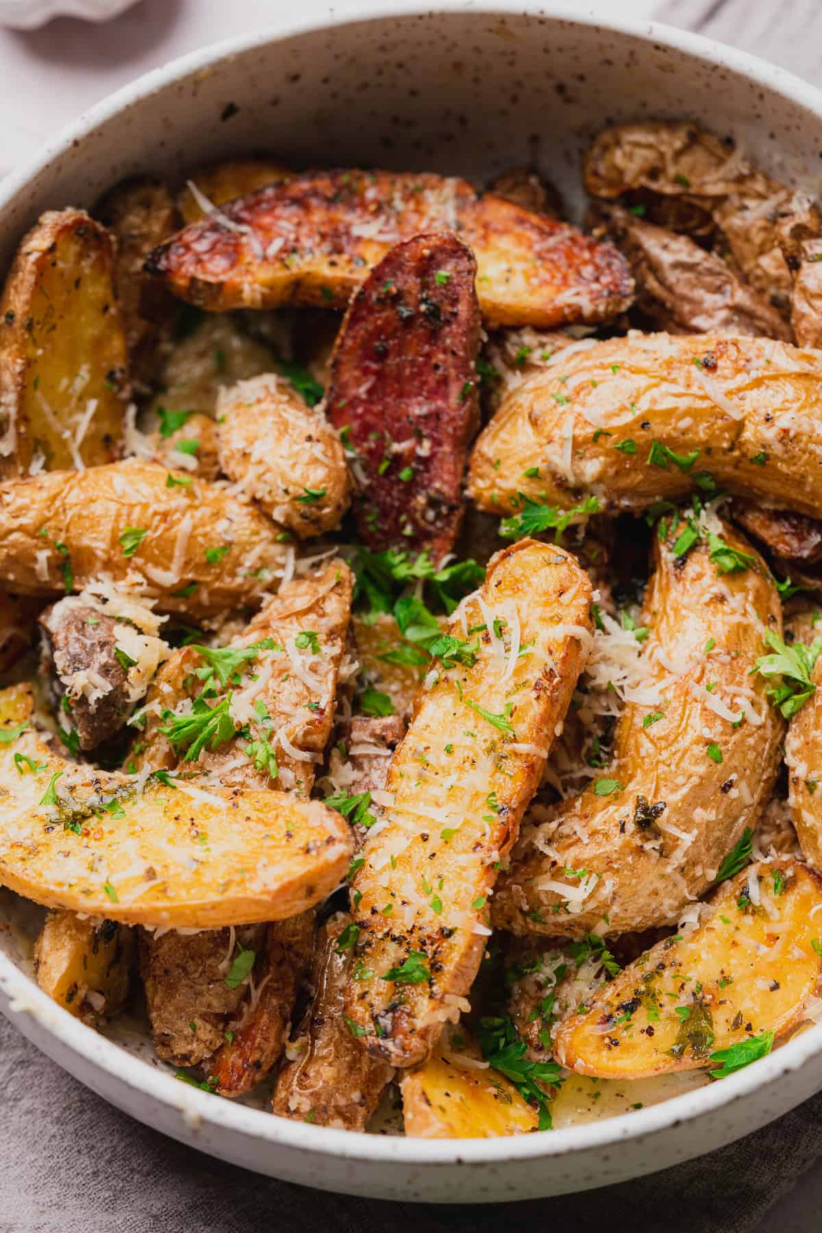 close up shot of air fryer fingerling potatoes with fresh parsley and parmesan cheese