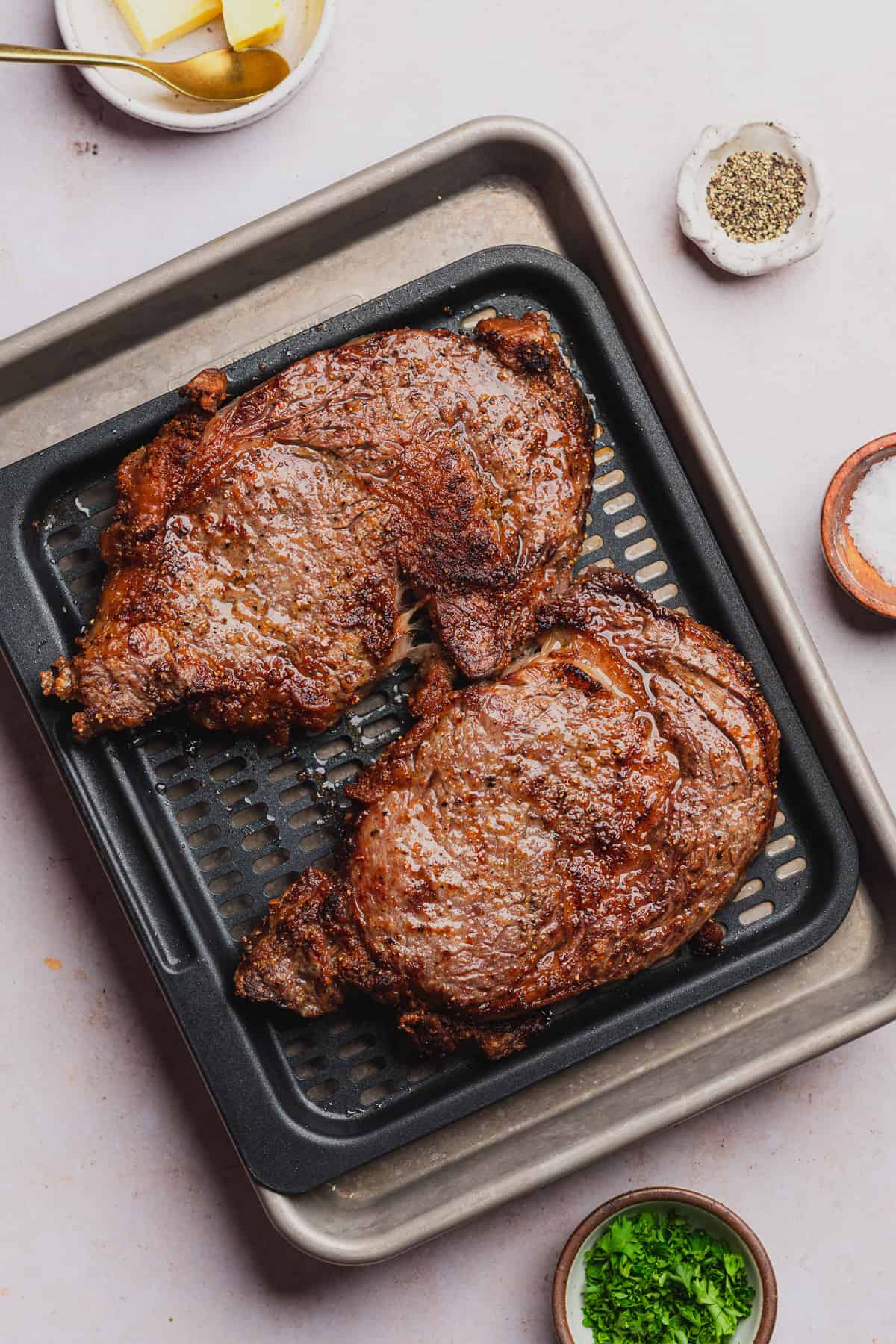 two air fryer ribeyes on an air fryer tray after being fully cooked 