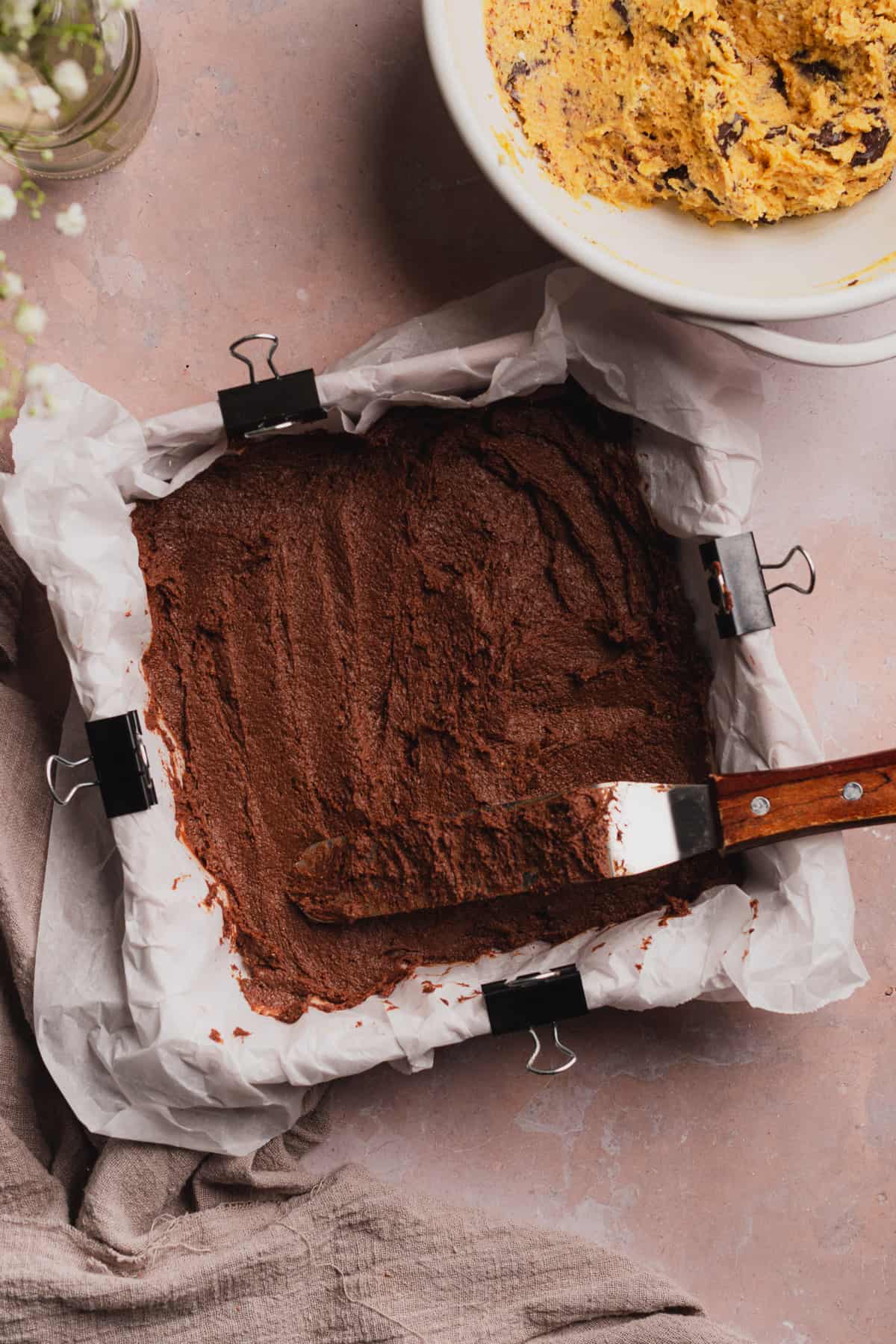 spreading brownie batter on in a baking pan with an angled spatula 