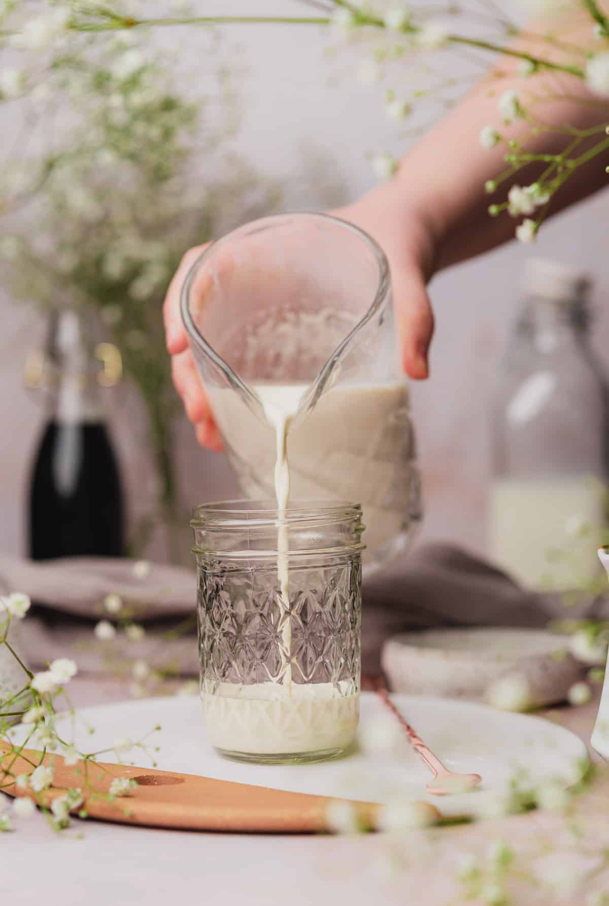 hand pouring vanilla sweet cream to a mason jar. 
