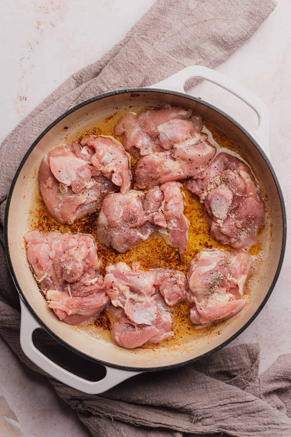 raw seasoned chicken thighs in an enameled dutch oven